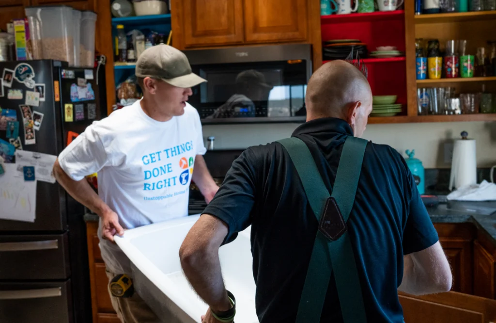 Two handyman pros carrying kitchen sink