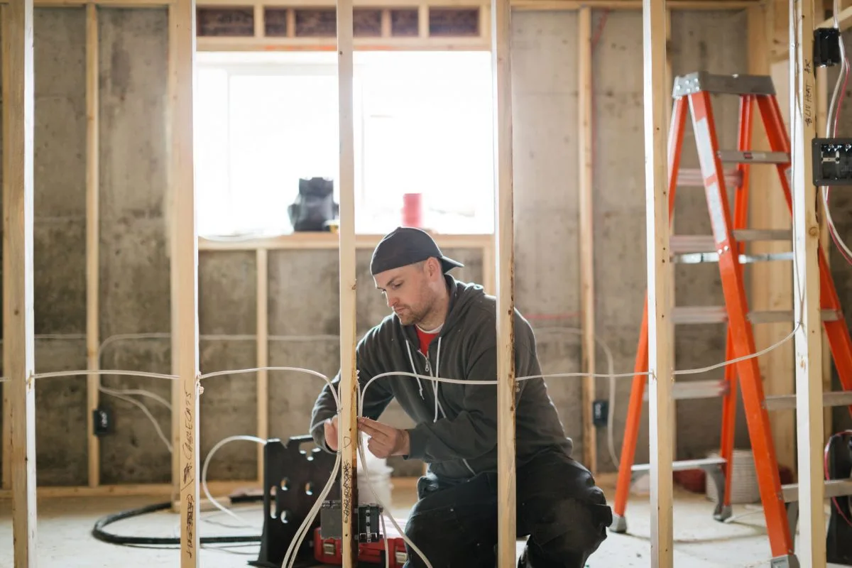 Electrician installing wire through wall wood framing