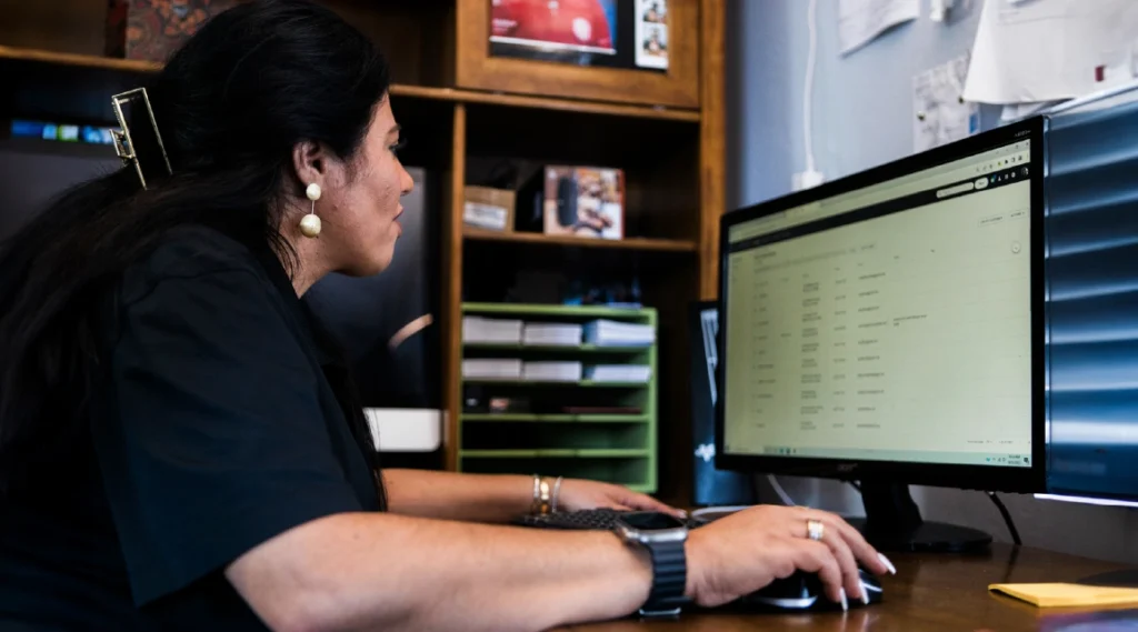 Woman cleaning business owner views desktop screen in her office