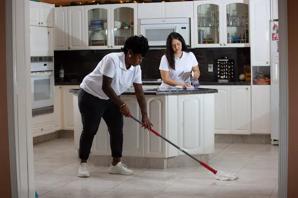 two female home cleaning pros at work in kitchen